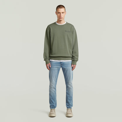 Modelo luciendo sudadera con logotipo de los 90 en color verde, con cuello redondo y diseño atemporal.