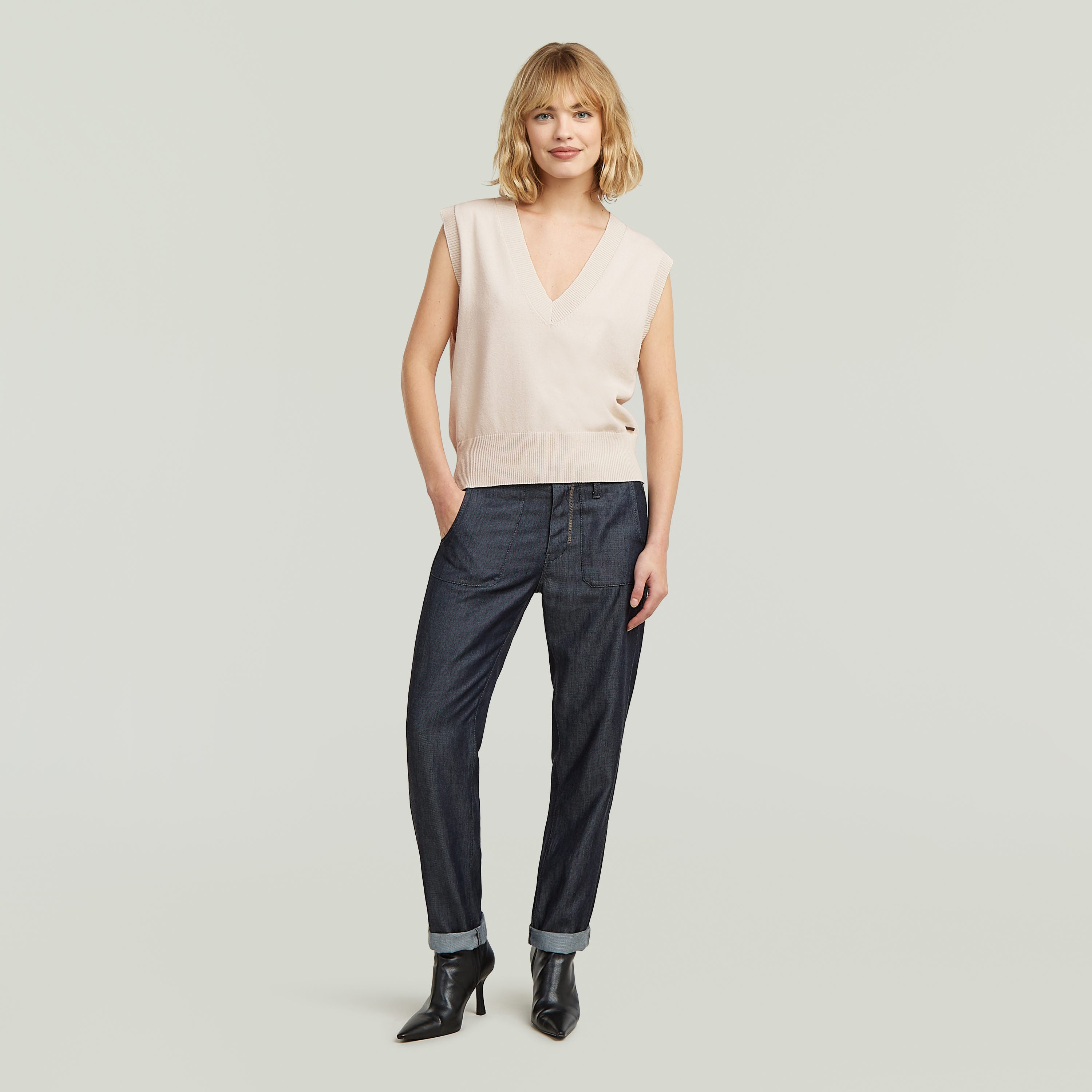 Modelo con chaleco de punto holgado color blanco y pantalones oscuros, luciendo un estilo relajado.