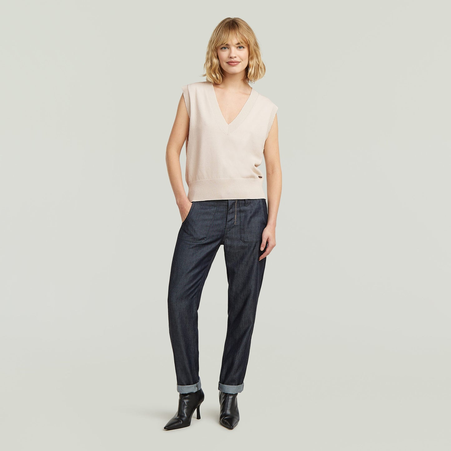 Modelo con chaleco de punto holgado color blanco y pantalones oscuros, luciendo un estilo relajado.