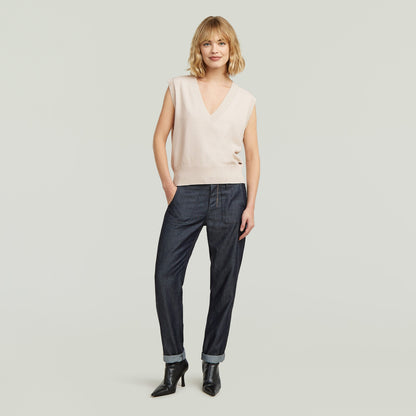 Modelo con chaleco de punto holgado color blanco y pantalones oscuros, luciendo un estilo relajado.