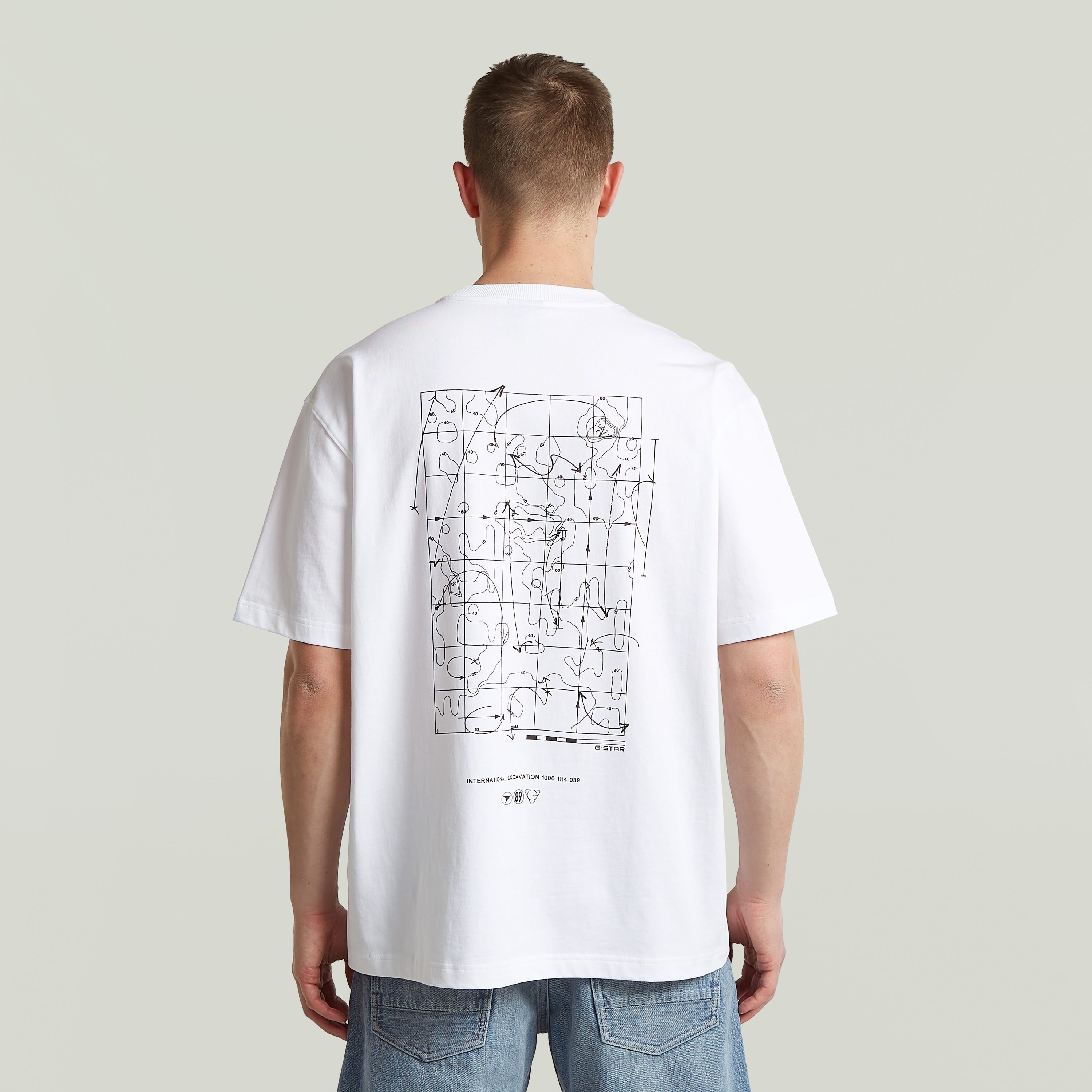 Back view of a man wearing a relaxed fit graphic tee with modern design on the back.