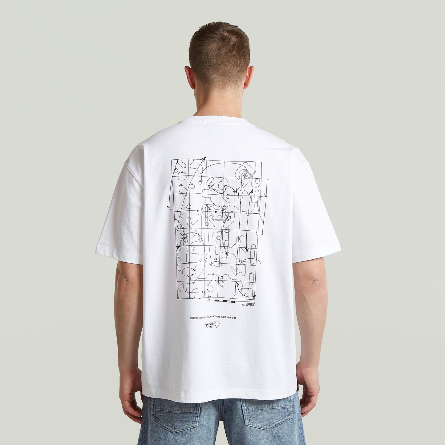 Back view of a man wearing a relaxed fit graphic tee with modern design on the back.