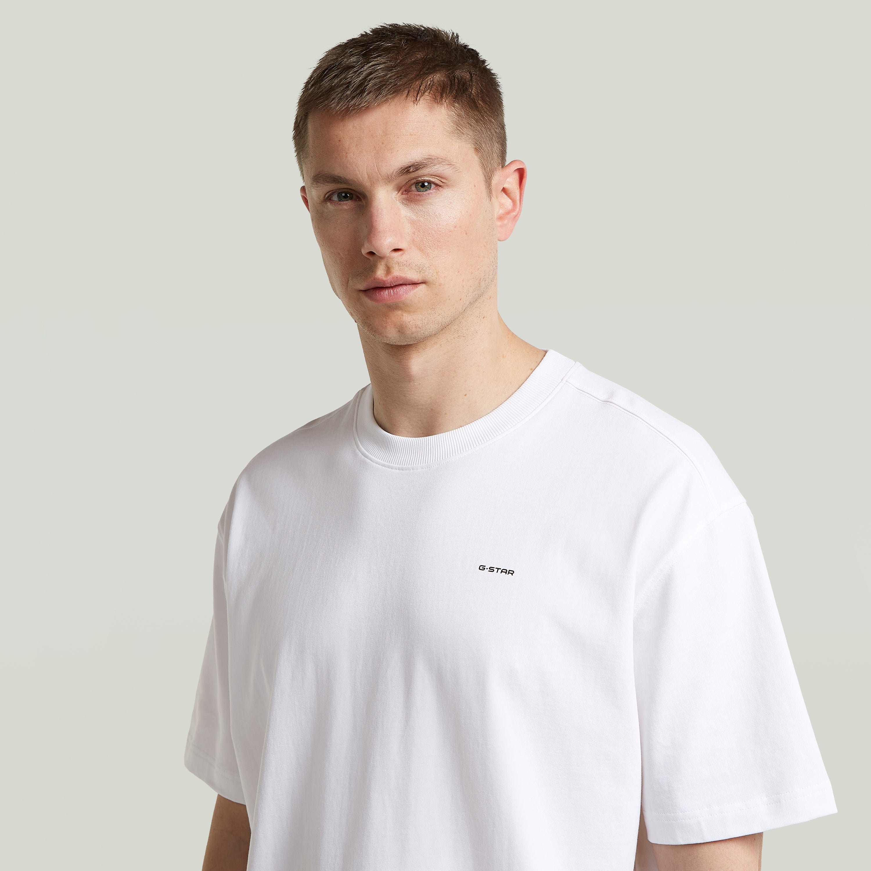 Model wearing relaxed fit graphic tee in white, featuring G-Star logo and relaxed cut for comfortable styling.