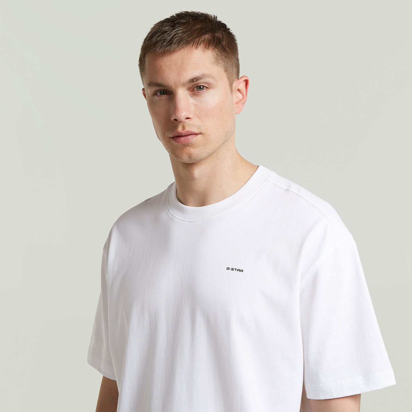 Model wearing relaxed fit graphic tee in white, featuring G-Star logo and relaxed cut for comfortable styling.