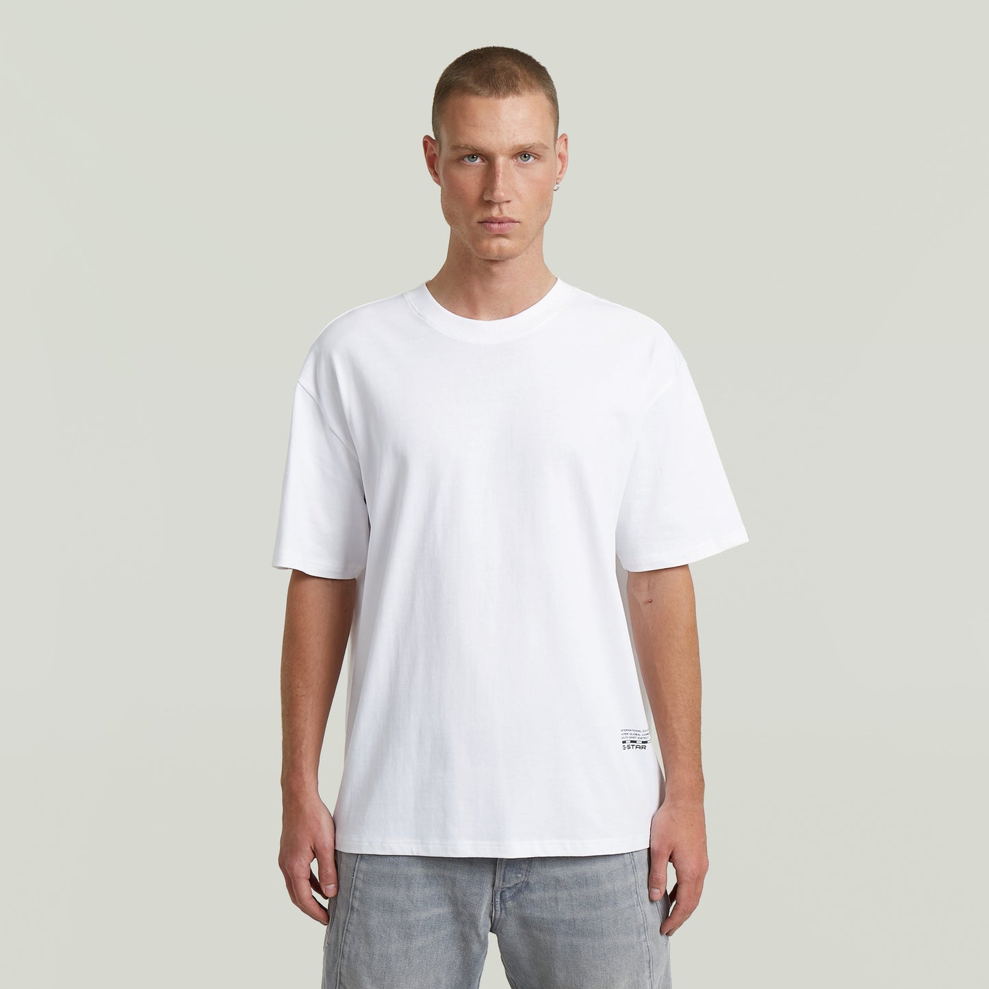 Modelo masculino luciendo la camiseta Back Applique Relaxed, blanca, de corte relajado y cuello redondo.