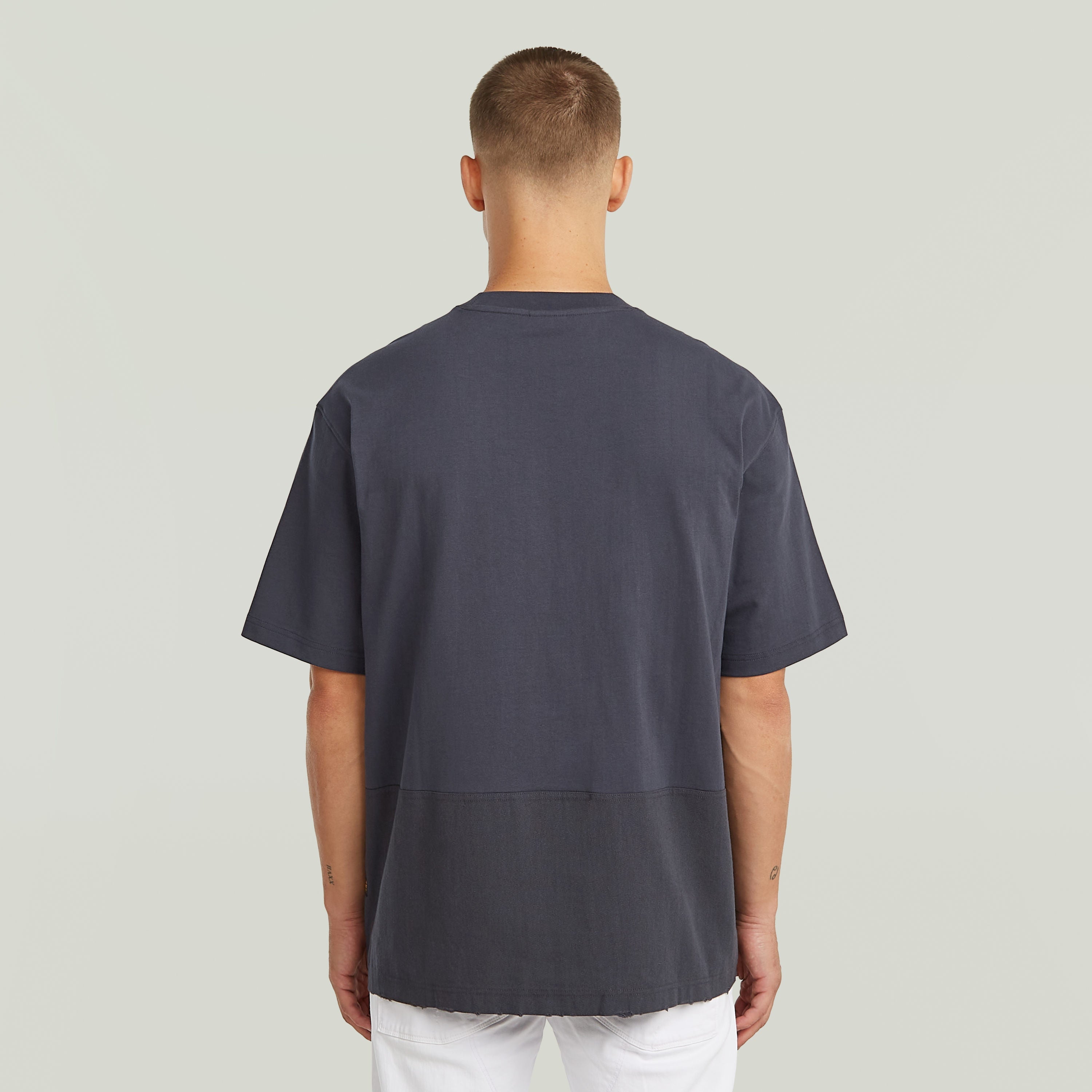 Hombre usando una camiseta Utility Fabric Mix gris con corte suelto y cuello redondo desde atrás.