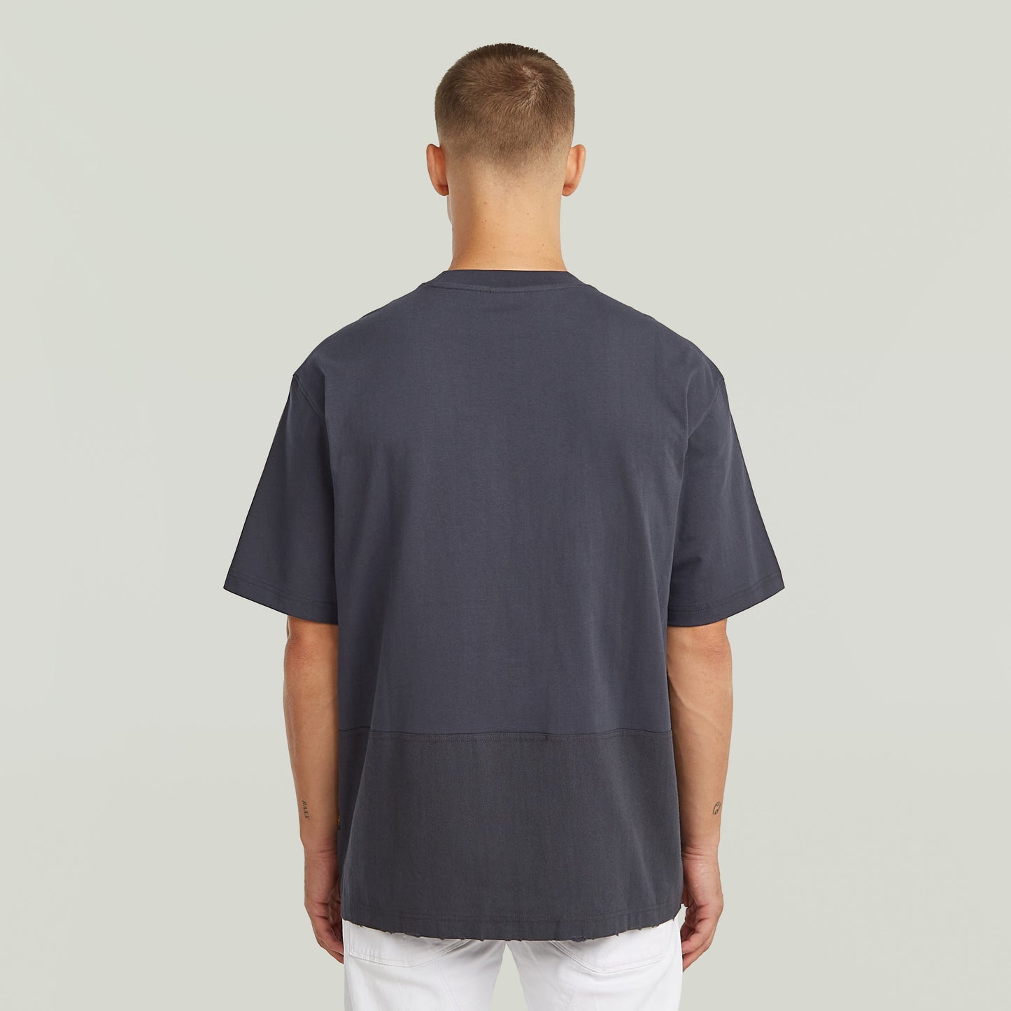 Hombre usando una camiseta Utility Fabric Mix gris con corte suelto y cuello redondo desde atrás.