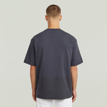 Hombre usando una camiseta Utility Fabric Mix gris con corte suelto y cuello redondo desde atrás.