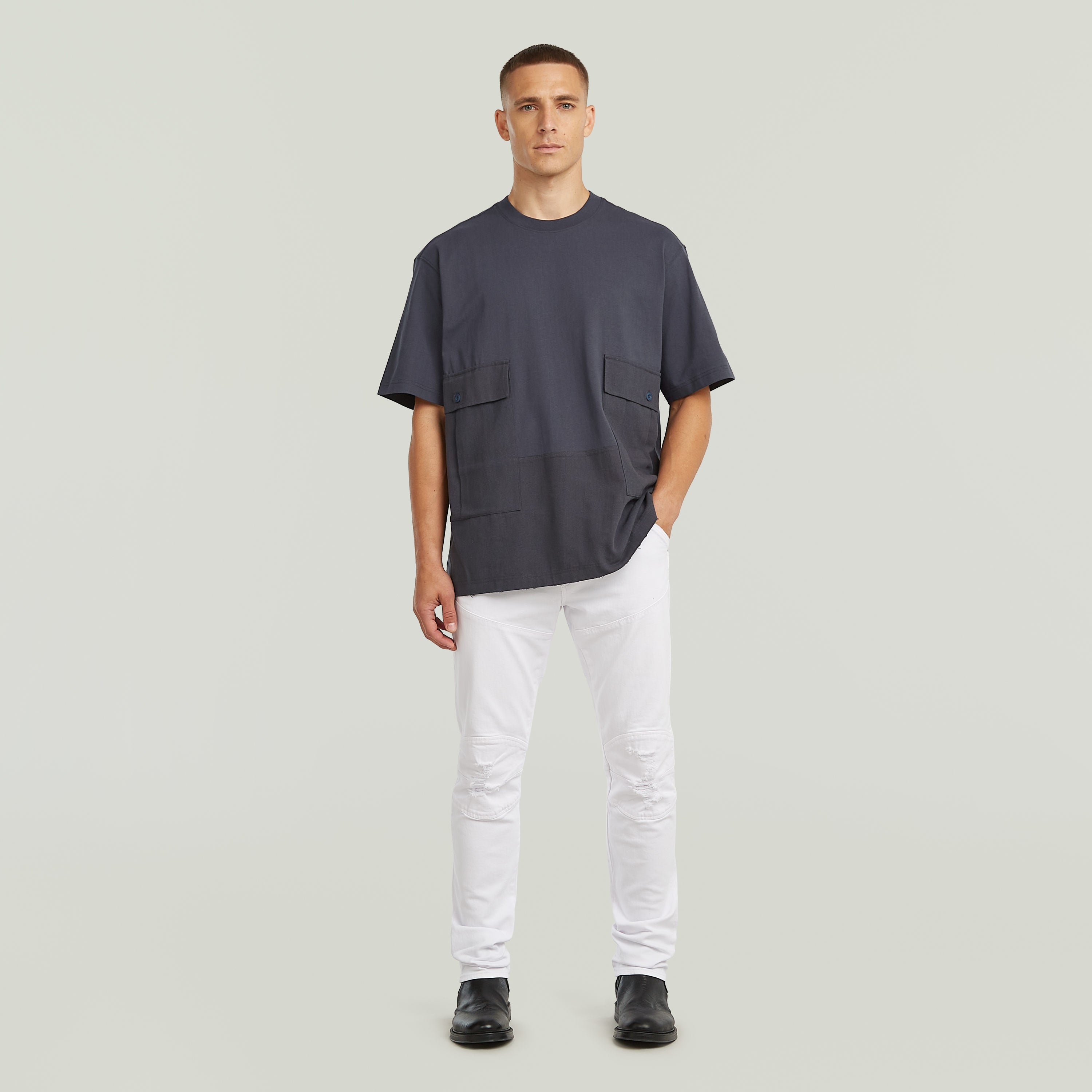 Model wearing a utility fabric mix t-shirt with two front pockets, relaxed fit, in gray color.
