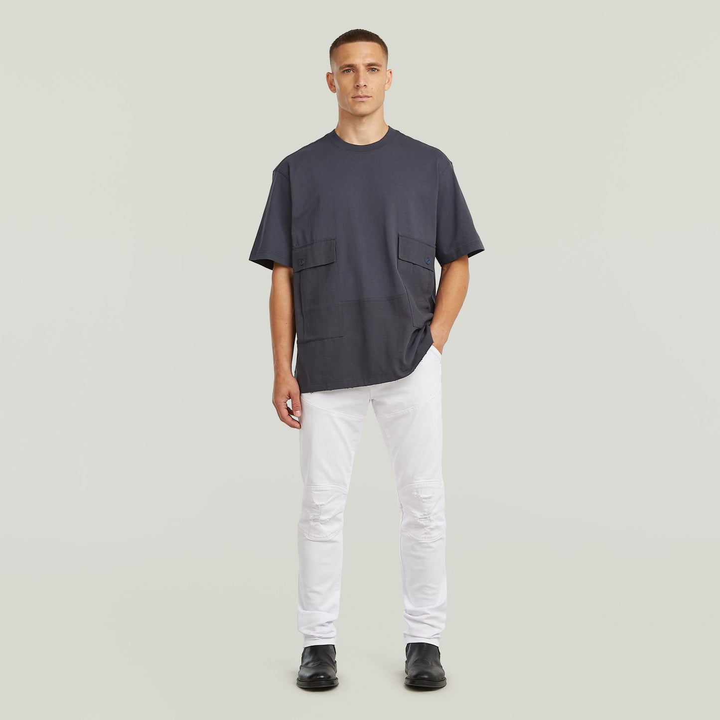 Model wearing a utility fabric mix t-shirt with two front pockets, relaxed fit, in gray color.