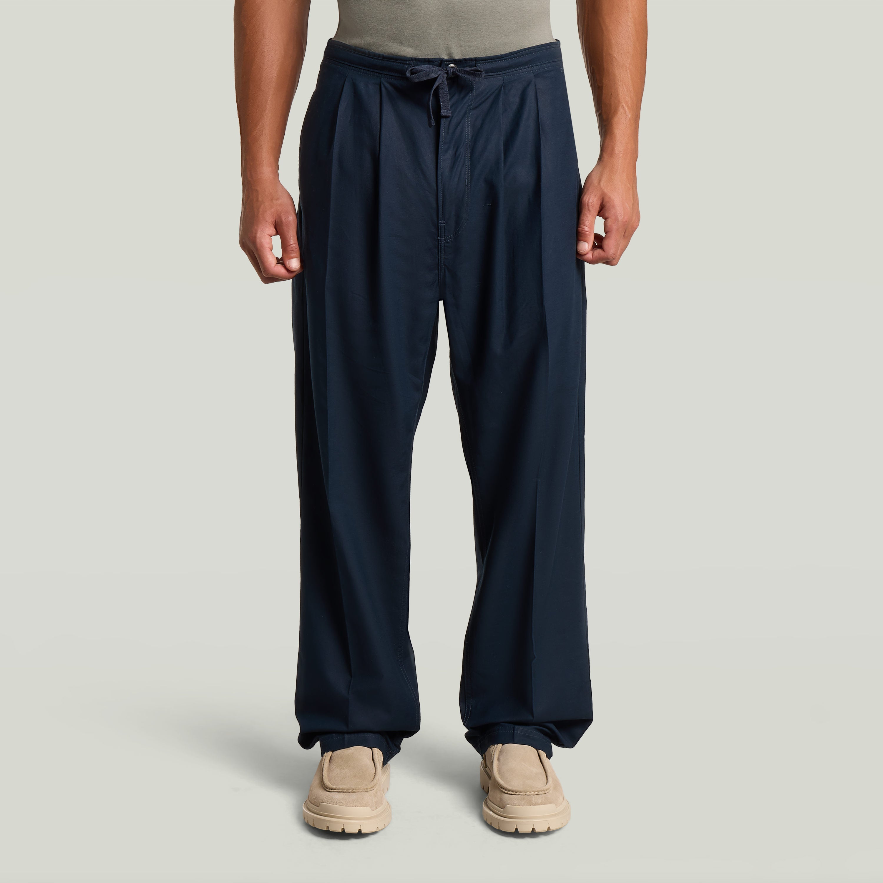 Chino con plisado doble en color azul oscuro, detalle de ajuste cónico y cintura media, con diseño moderno y clásico.
