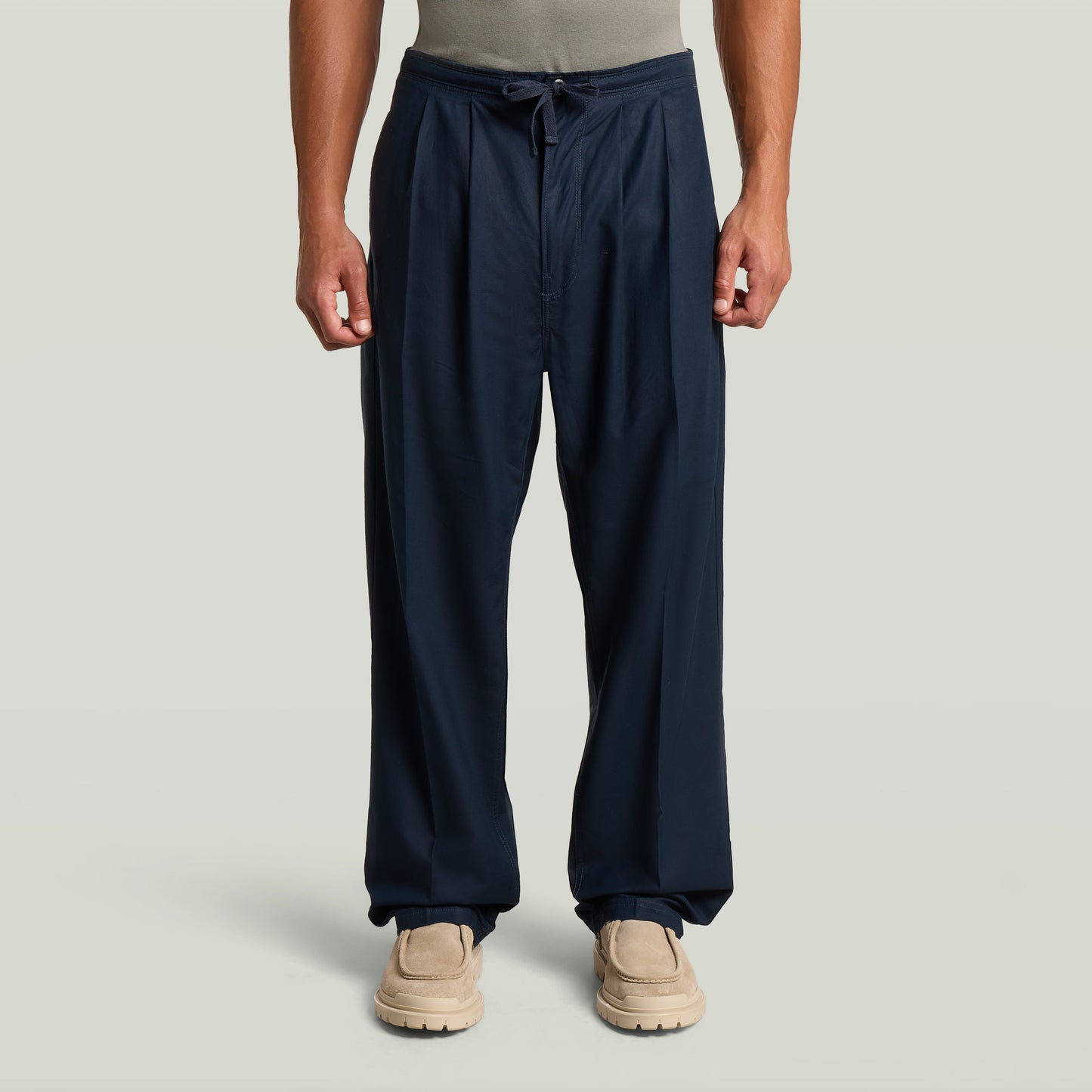 Chino con plisado doble en color azul oscuro, detalle de ajuste cónico y cintura media, con diseño moderno y clásico.