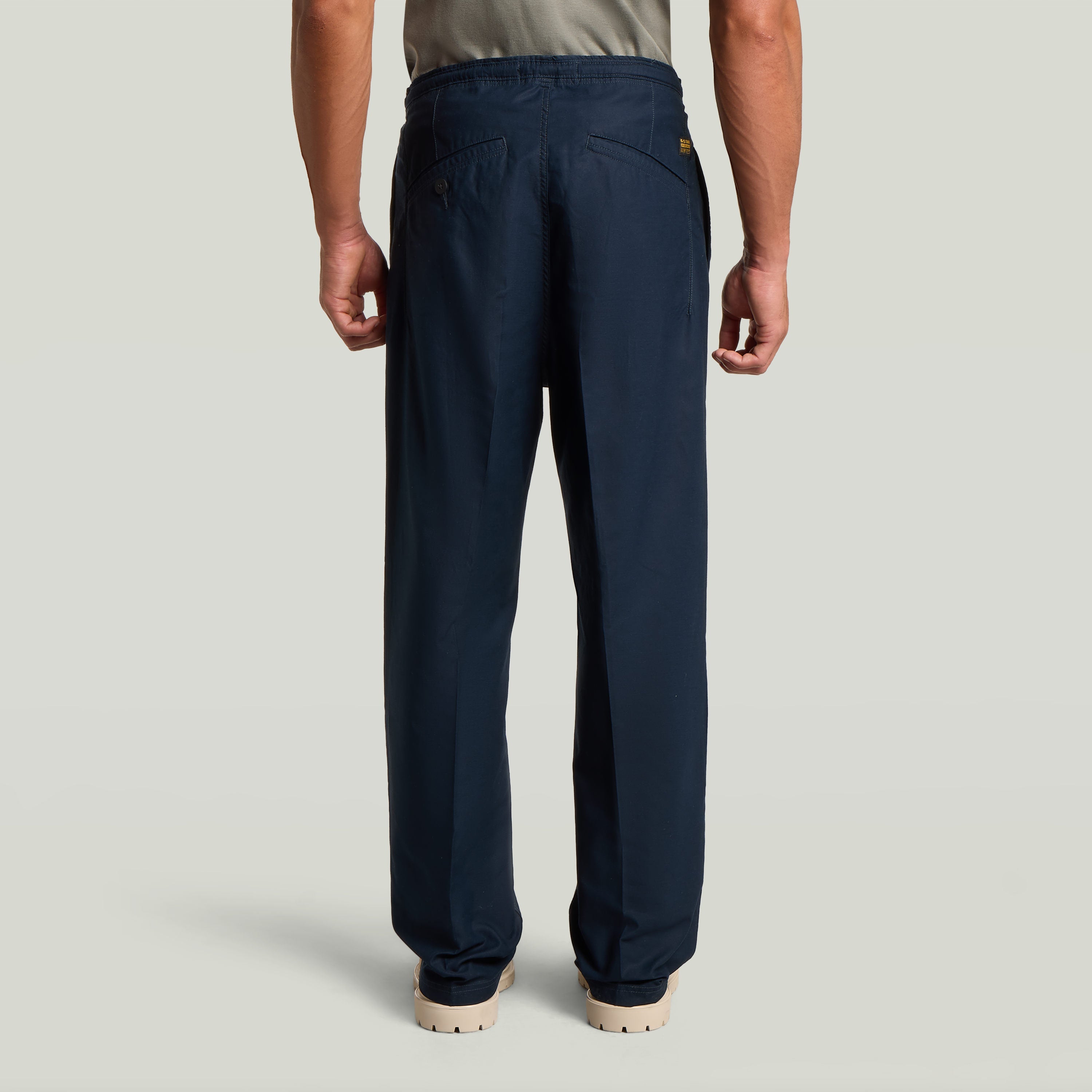 Vista trasera del Chino con plisado doble en color azul oscuro, destacando su diseño moderno y ajuste cónico.