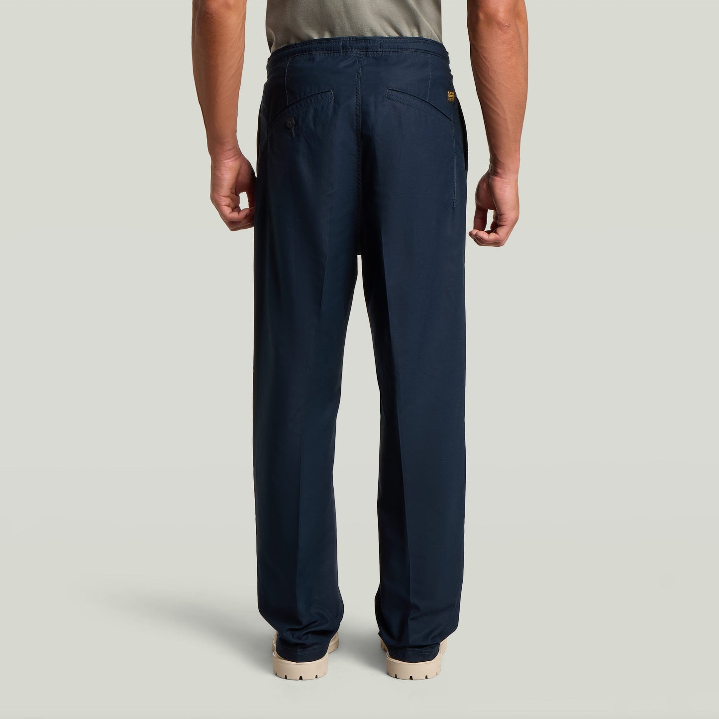 Vista trasera del Chino con plisado doble en color azul oscuro, destacando su diseño moderno y ajuste cónico.