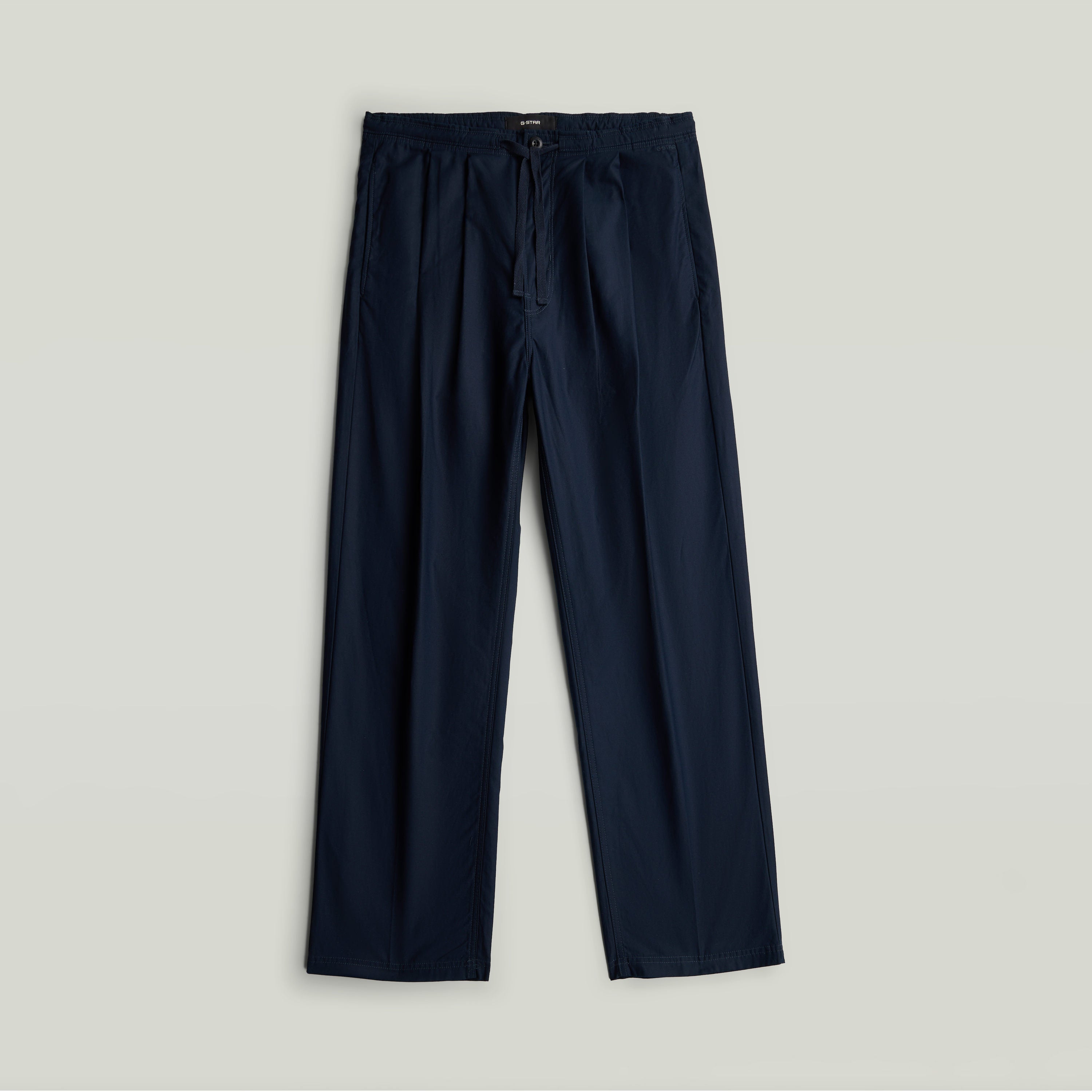 Chino con plisado doble en color azul oscuro, con diseño cónico y construcción de cintura media.