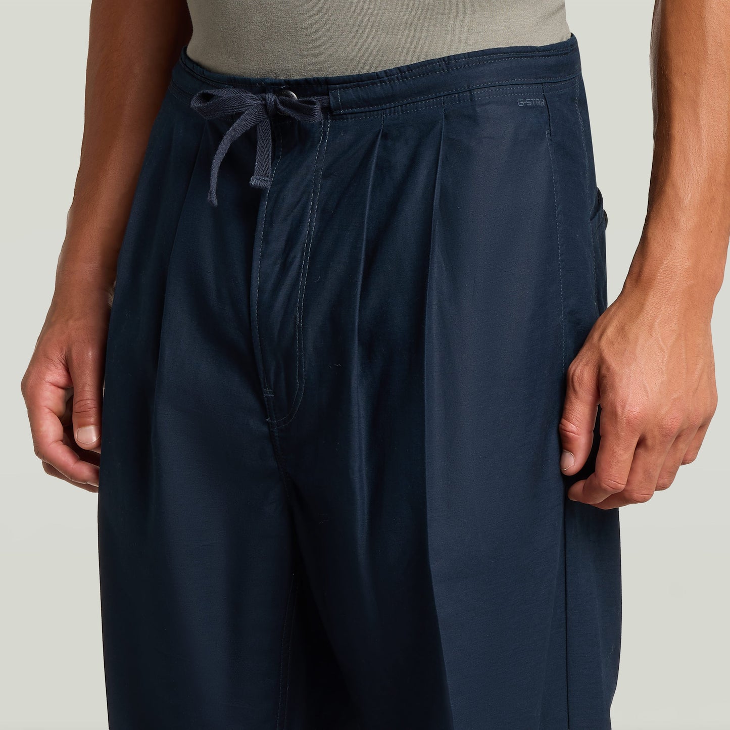 Chino con plisado doble en color azul oscuro, ajuste cónico y cintura media, ideal para un look moderno y clásico.