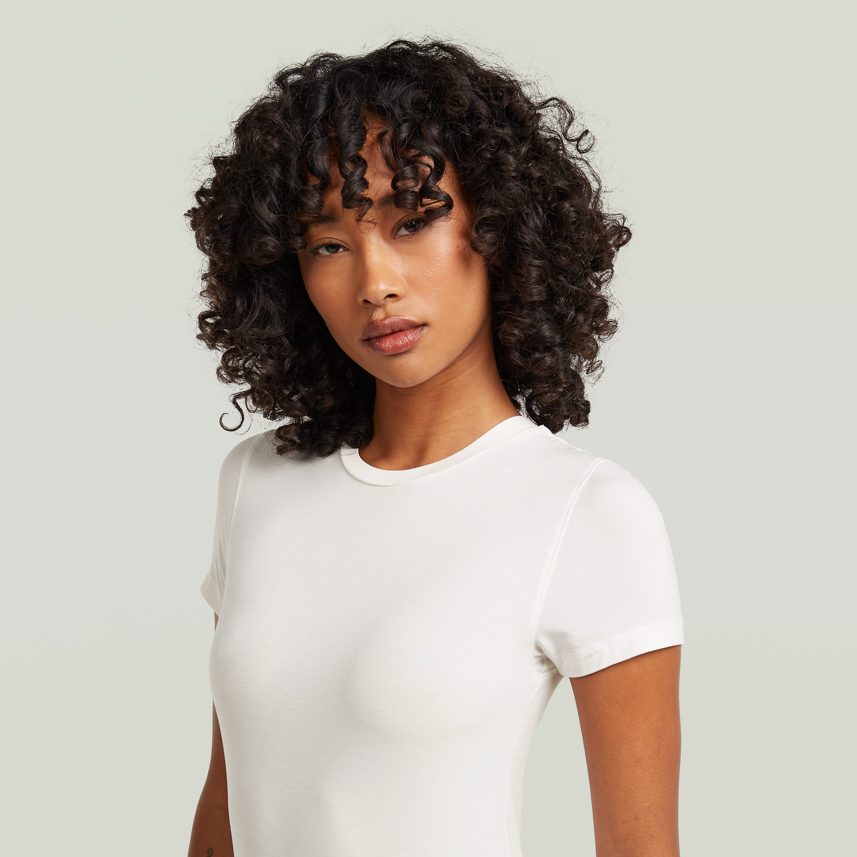 Mujer con camiseta ajustada de modal blanca, estilo elegante y cómodo, con cuello redondo y manga corta.