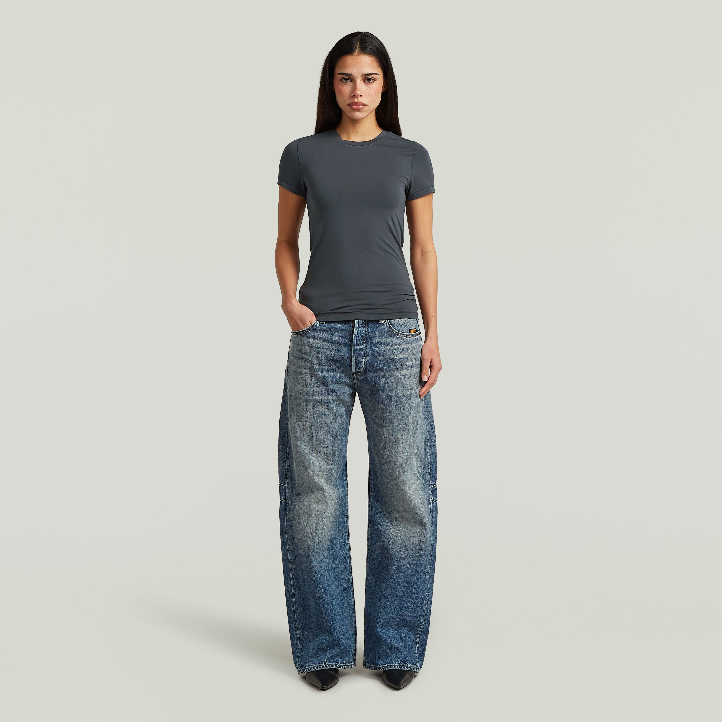 Mujer con camiseta 2nd skin fitted t-shirt gris y jeans anchos, estilo elegante y cómodo.