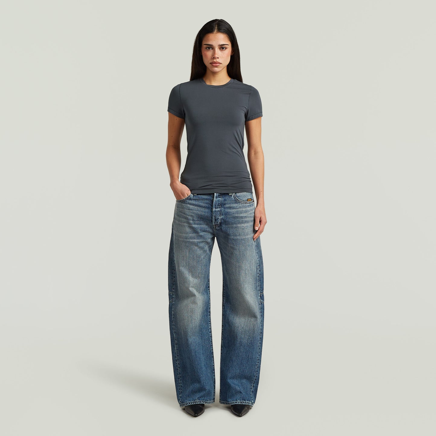 Mujer con camiseta 2nd skin fitted t-shirt gris y jeans anchos, estilo elegante y cómodo.