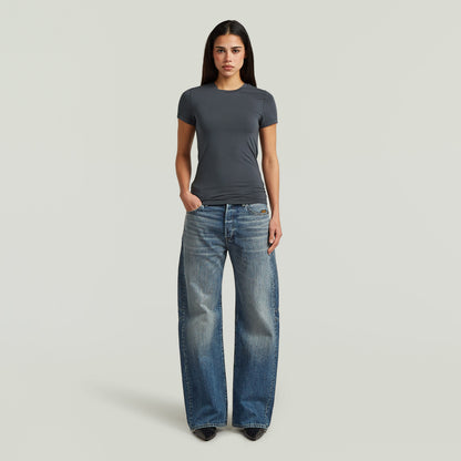 Mujer con camiseta 2nd skin fitted t-shirt gris y jeans anchos, estilo elegante y cómodo.