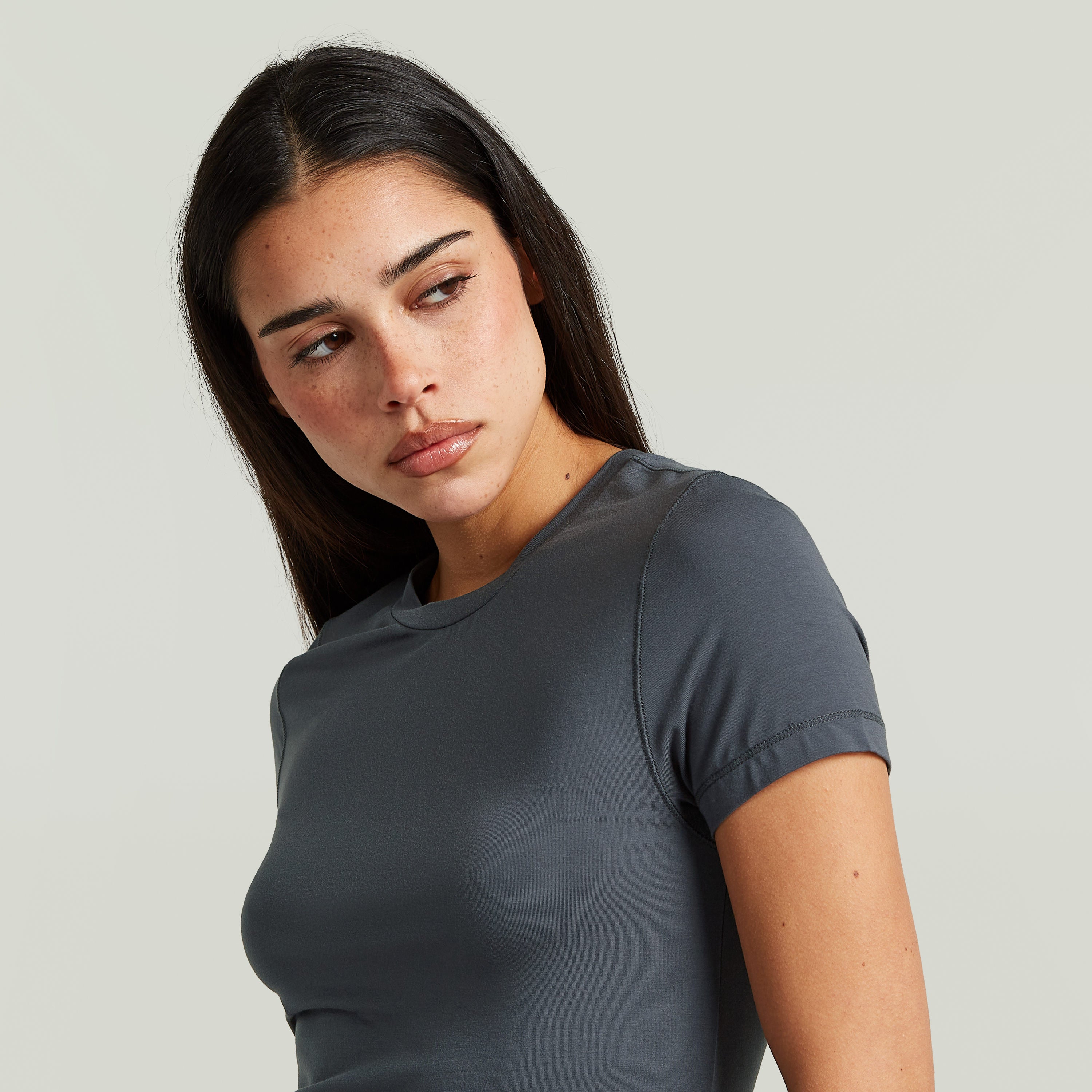 Modelo usando una camiseta 2nd Skin, una camiseta ajustada de color gris con cuello redondo y manga corta.