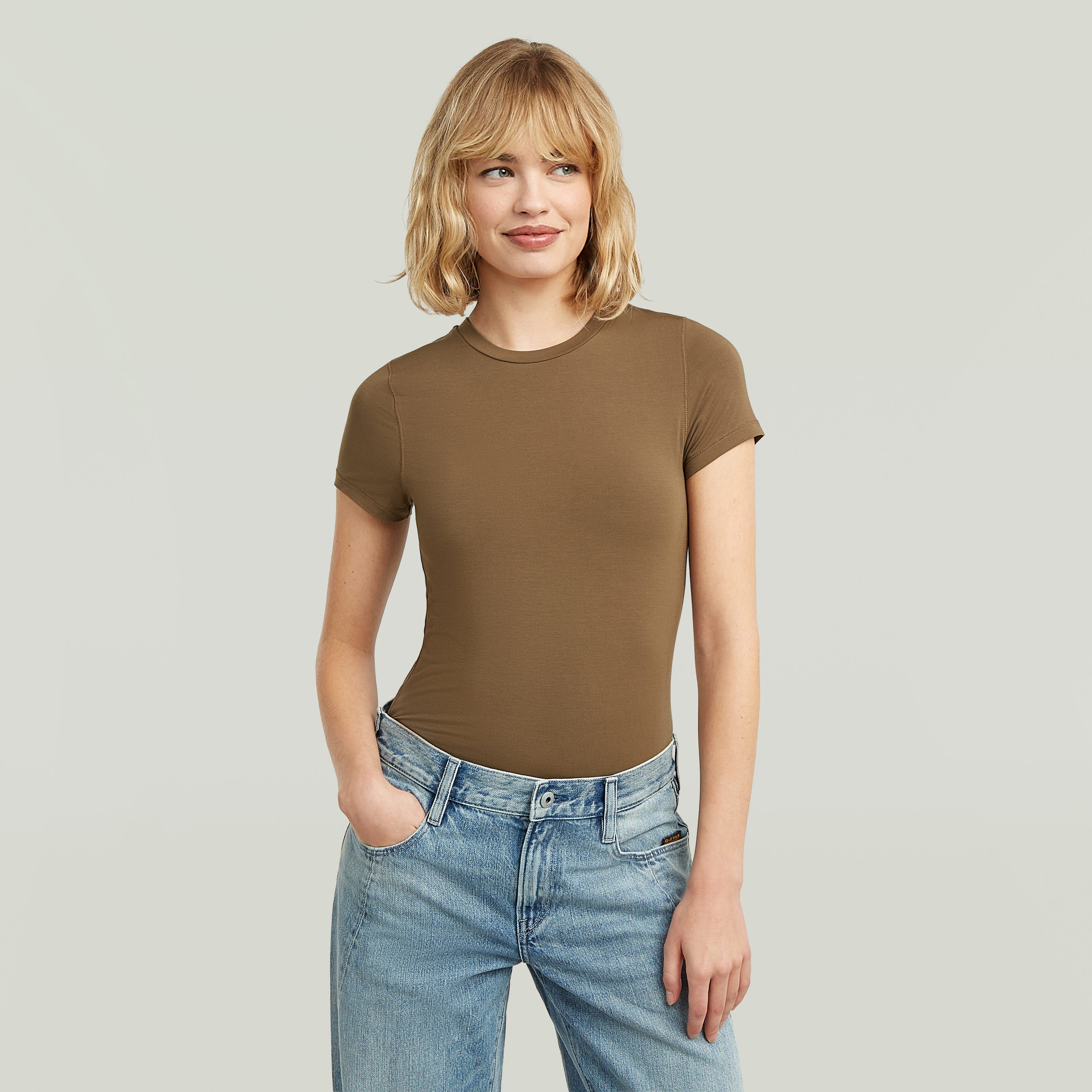Mujer luciendo una ajustada camiseta de modal marrón con corte elegante y cómodo.