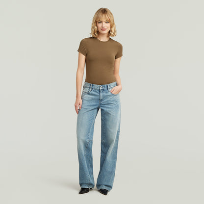 Mujer usando una ajustada camiseta de modal marrón y jeans holgados, con un look cómodo y elegante.