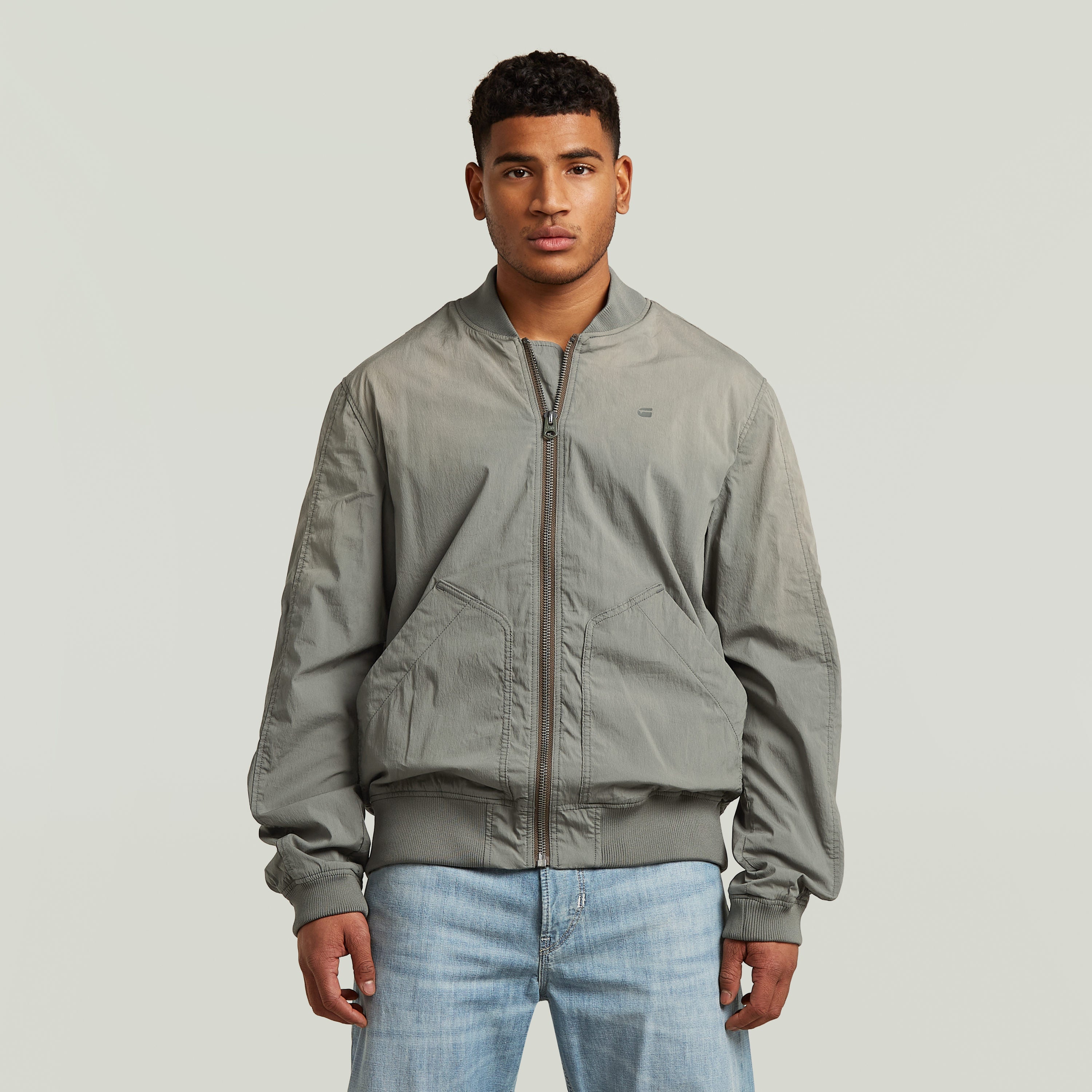 Modelo luciendo una cazadora Sunfaded Bomber gris con cierre de cremallera y cuello acanalado.