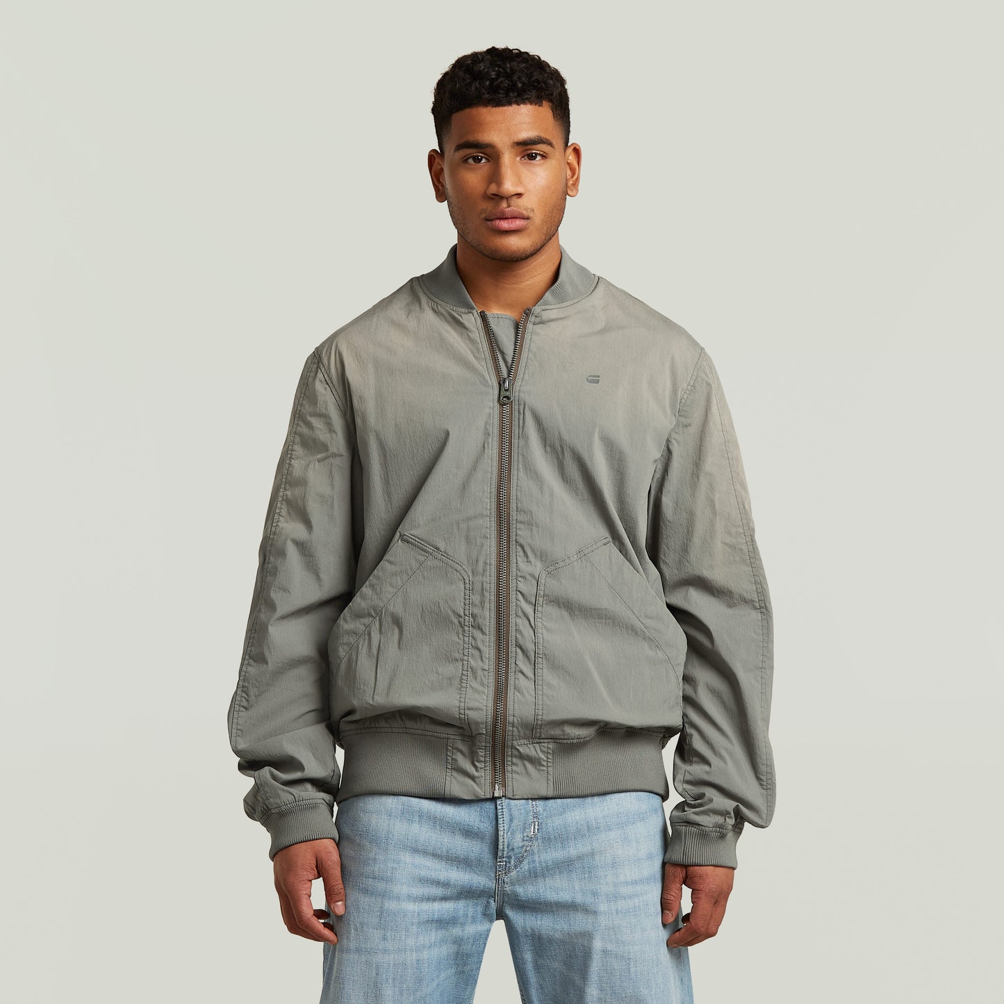 Modelo luciendo una cazadora Sunfaded Bomber gris con cierre de cremallera y cuello acanalado.