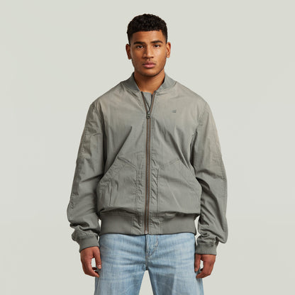 Modelo luciendo una cazadora Sunfaded Bomber gris con cierre de cremallera y cuello acanalado.