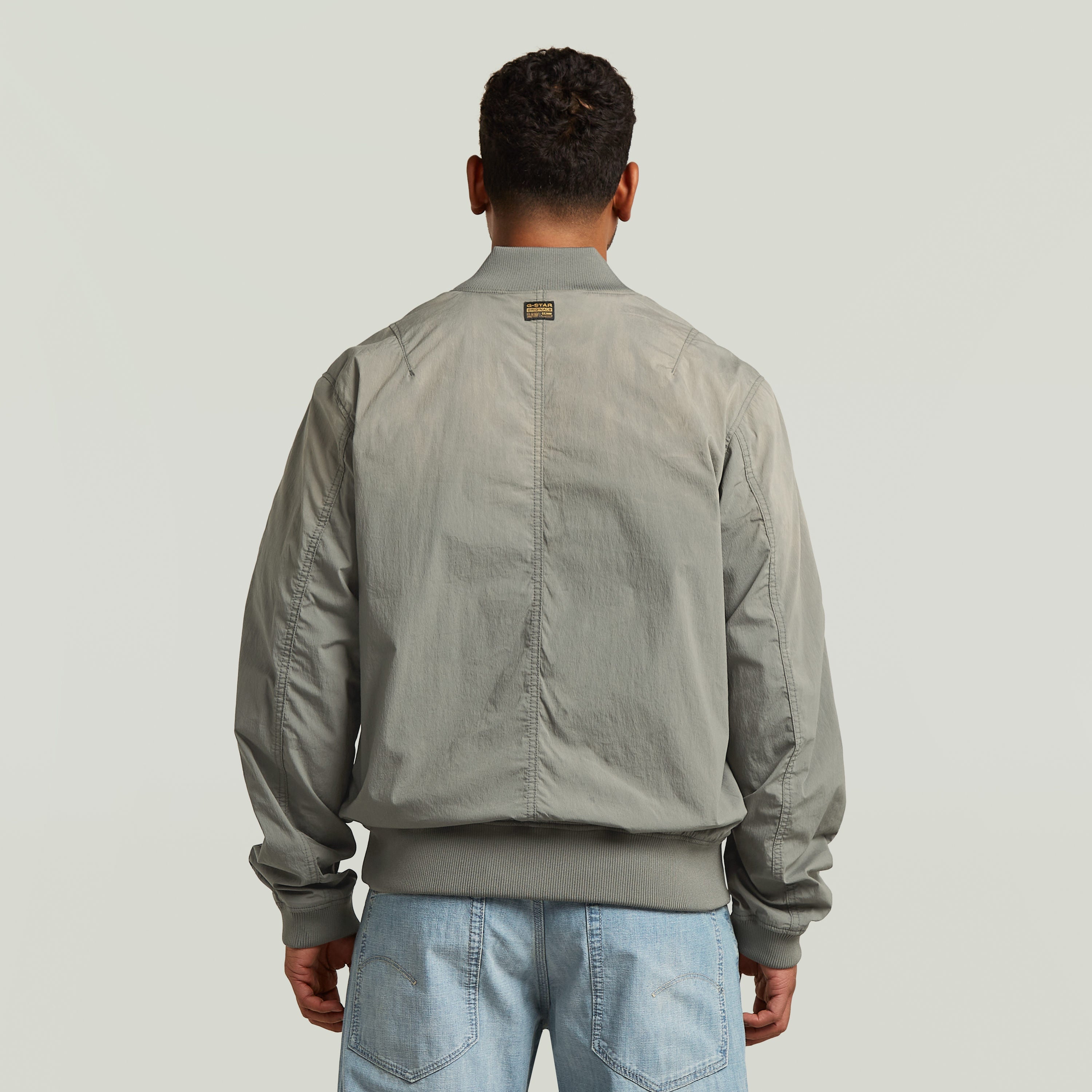 Vista trasera de la cazadora Sunfaded Bomber en color verde, con corte regular y cuello acanalado.