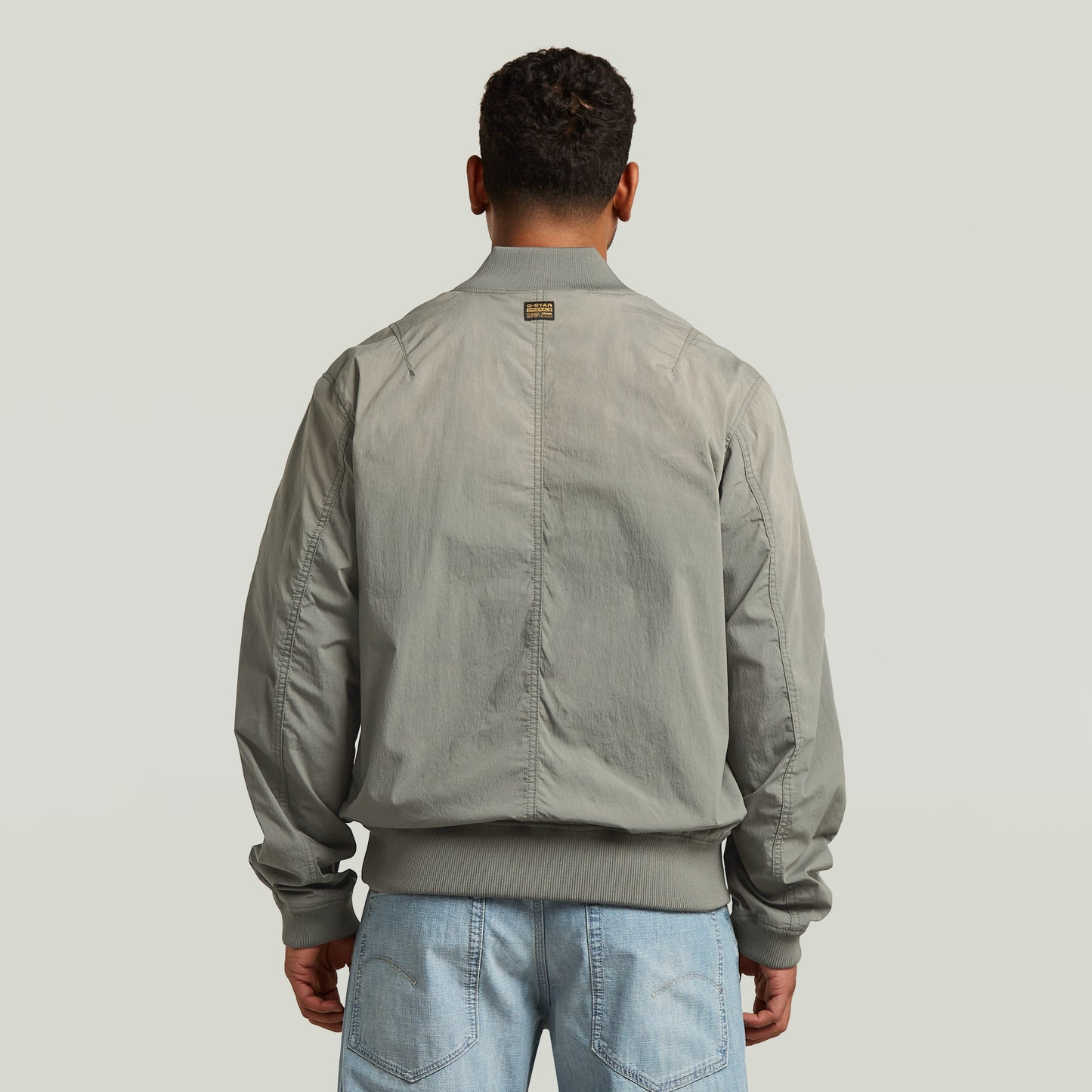 Vista trasera de la cazadora Sunfaded Bomber en color verde, con corte regular y cuello acanalado.