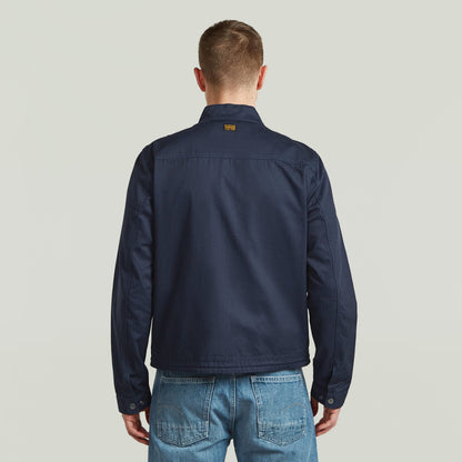Chaqueta ligera de algodón reciclado vista desde atrás, hecha de 60% algodón y 40% algodón reciclado, color azul oscuro.