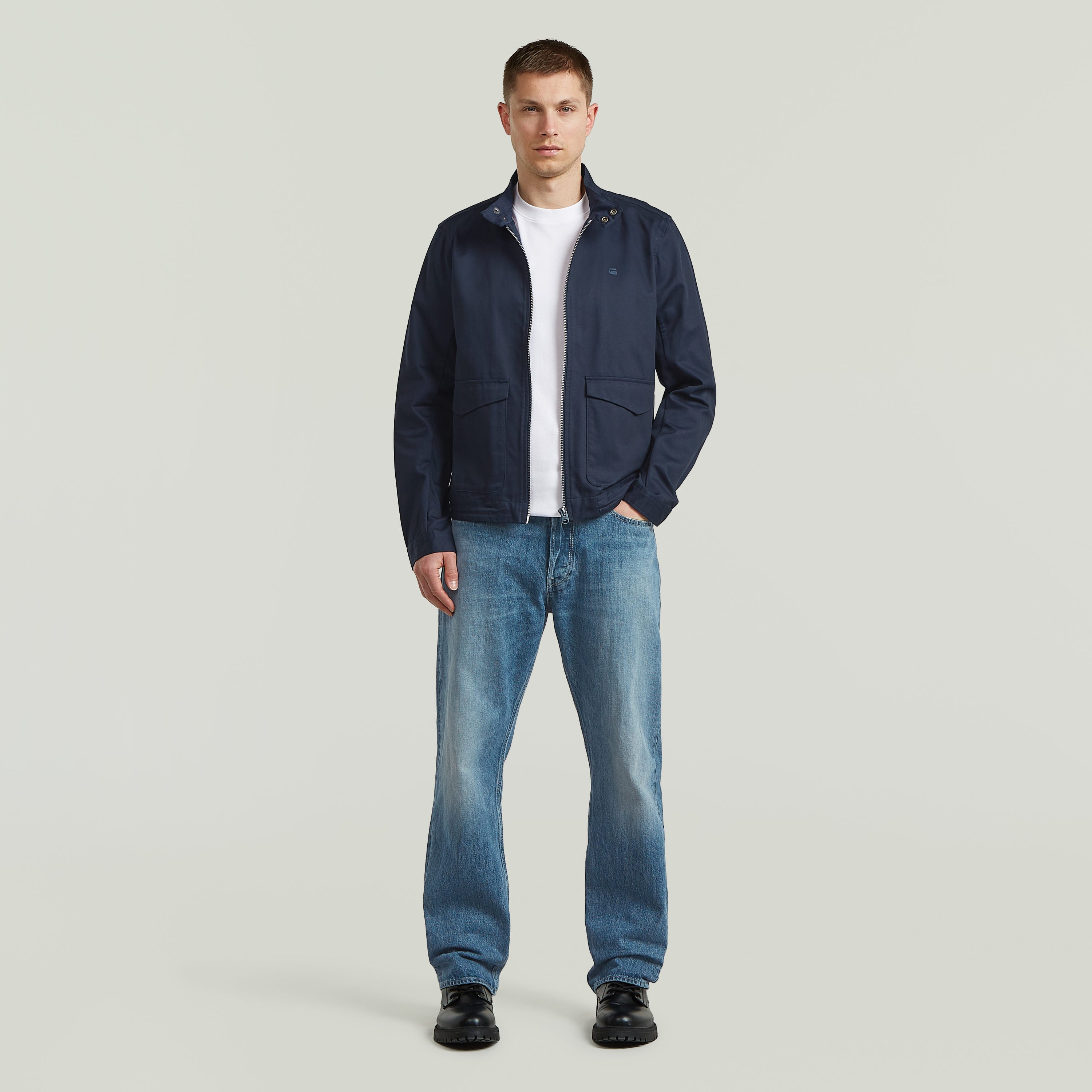 Modelo con chaqueta ligera de algodón reciclado de corte recto y color azul oscuro, combinada con jeans.