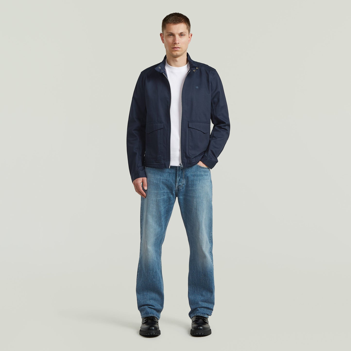 Modelo con chaqueta ligera de algodón reciclado de corte recto y color azul oscuro, combinada con jeans.