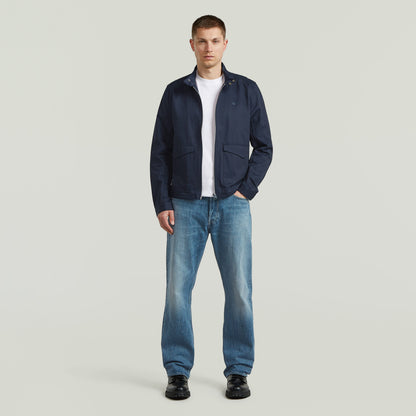 Modelo con chaqueta ligera de algodón reciclado de corte recto y color azul oscuro, combinada con jeans.
