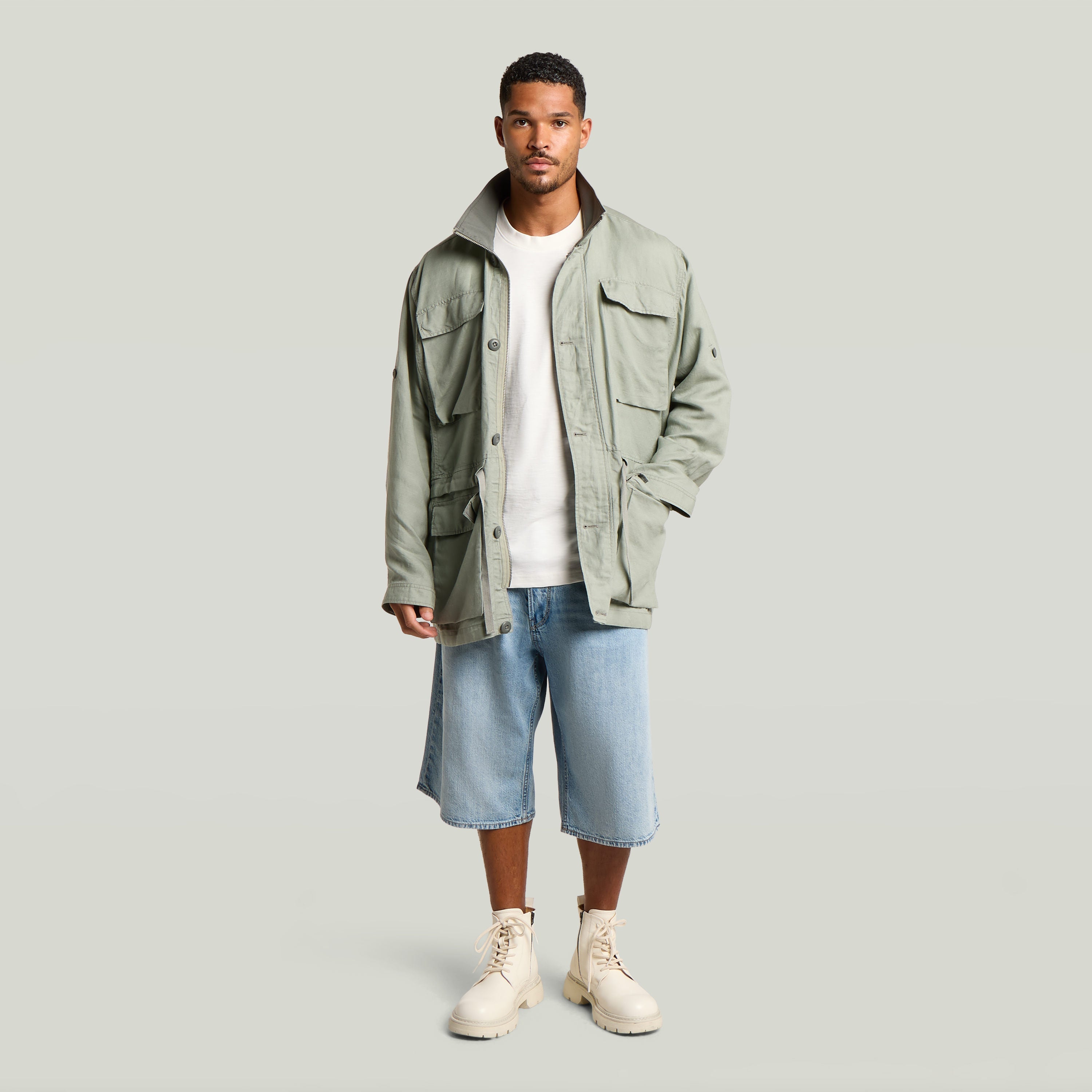 Versatile field smock jacket in green, worn by a man with beige boots and denim shorts.