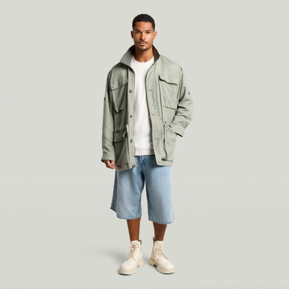 Versatile field smock jacket in green, worn by a man with beige boots and denim shorts.
