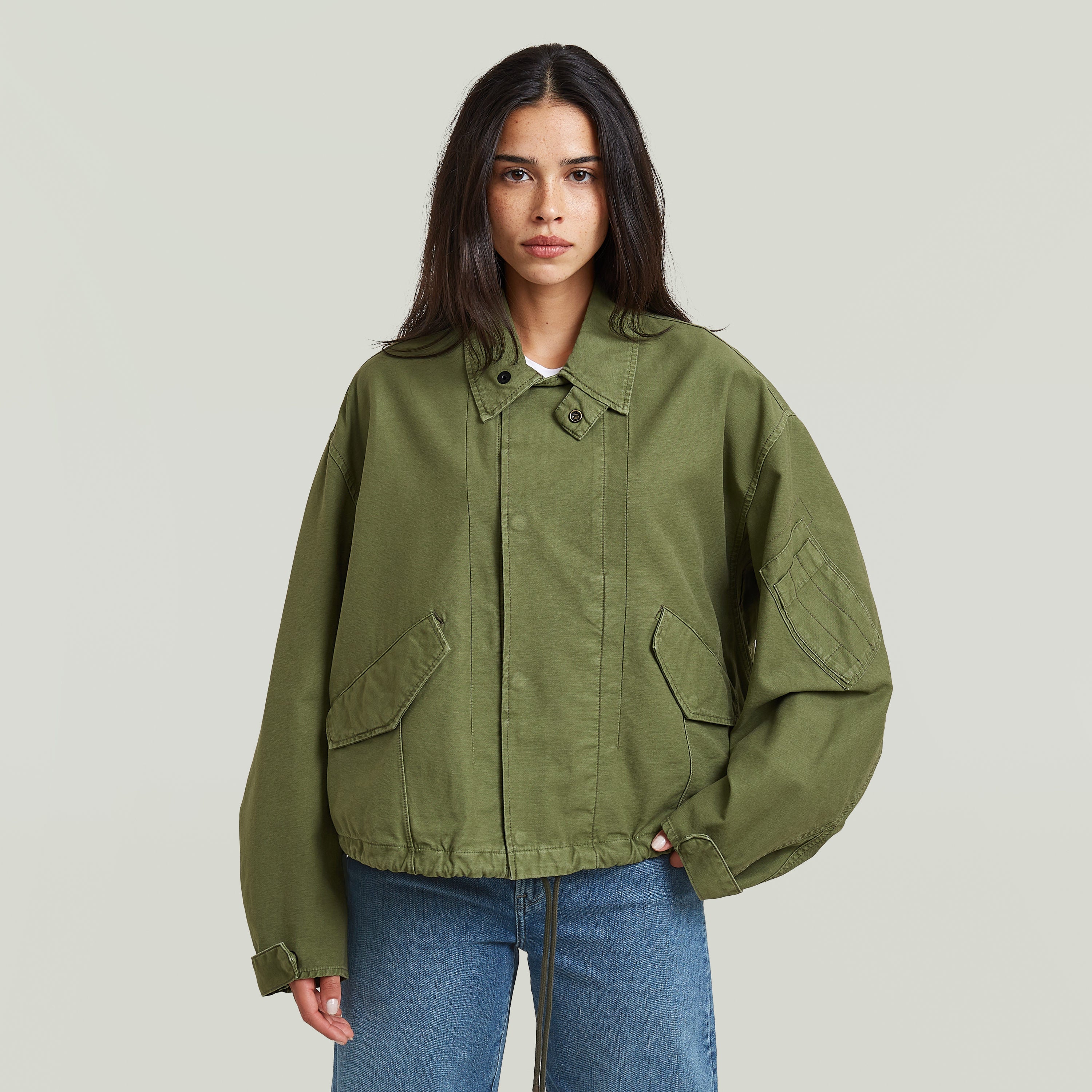 Modelo vistiendo una chaqueta oversized cropped verde con cuello de camisa y botones a presión.