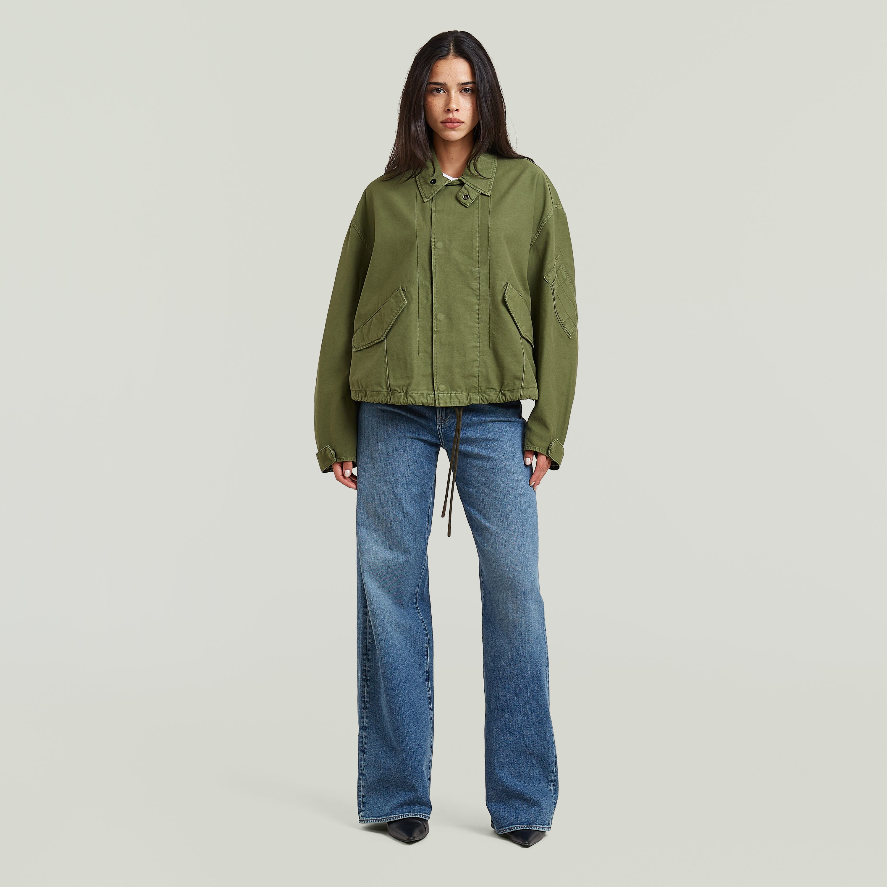 Mujer usando chaqueta oversized cropped verde con corte relajado y detalles de diseño.