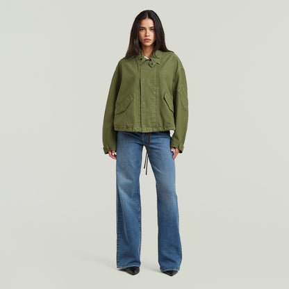 Mujer usando chaqueta oversized cropped verde con corte relajado y detalles de diseño.