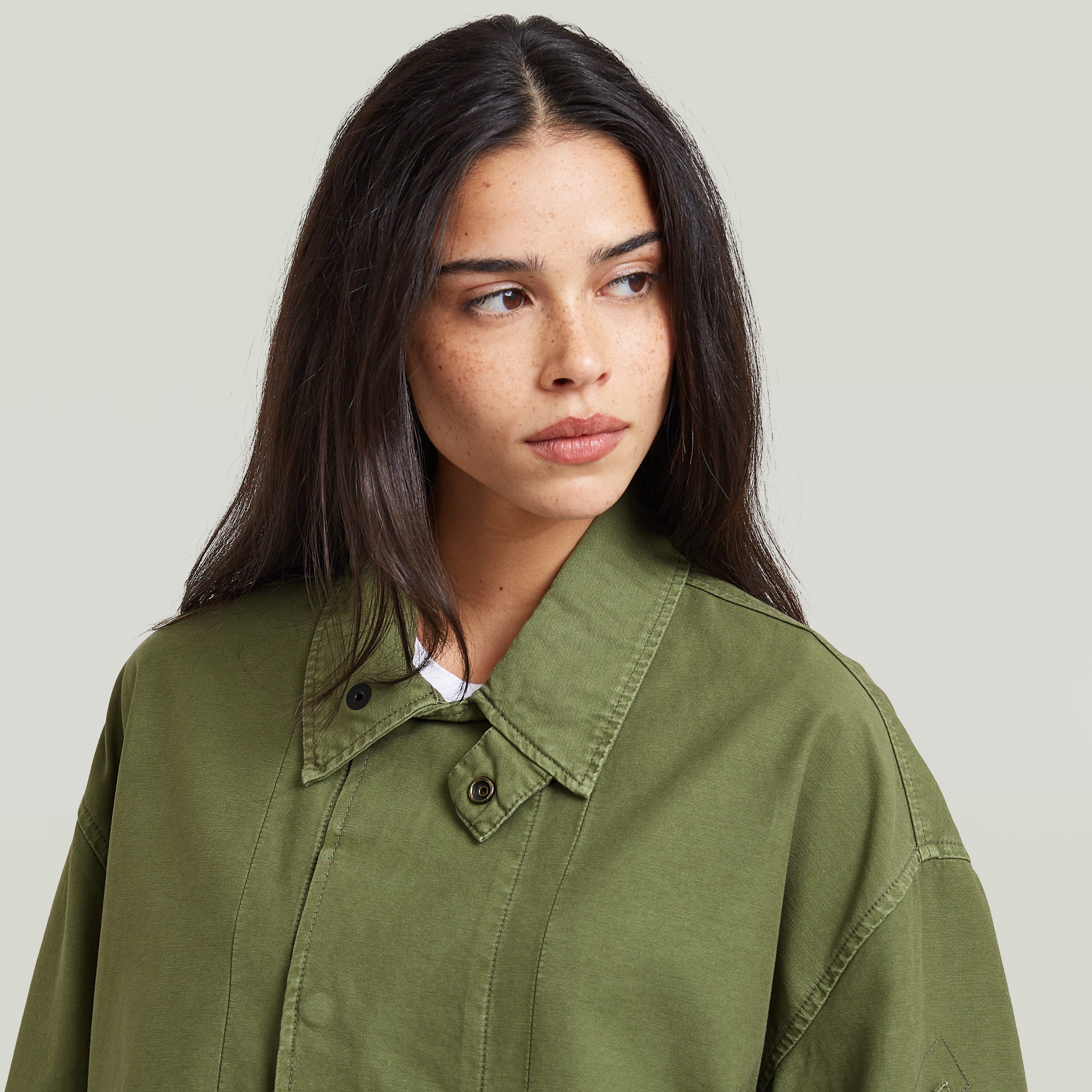 Mujer con chaqueta Oversized Cropped verde, corte corto, cuello de camisa y cierre a presión.