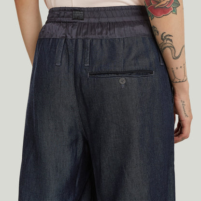pantalones fluidos de denim ligero, vista trasera con detalles de botón y bolsillos, diseño elegante y cómodo.