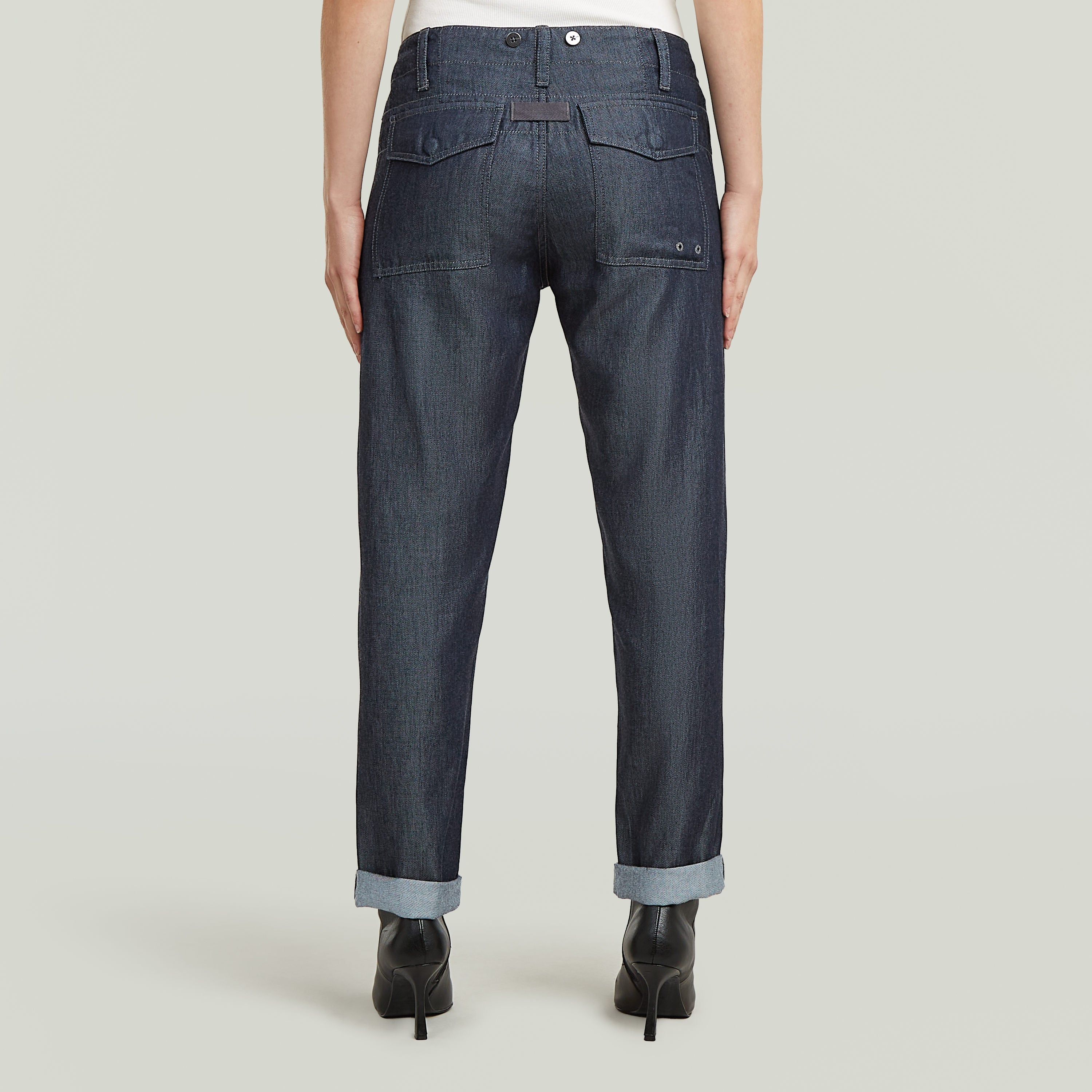 Vista trasera de los pantalones fatigue boyfriend ligeros de denim oscuro con detalles de bolsillos.