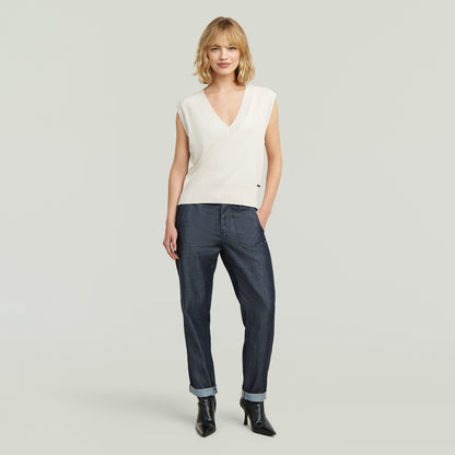 Mujer luciendo pantalones fatigue boyfriend ligeros en denim oscuro y top de punto blanco.