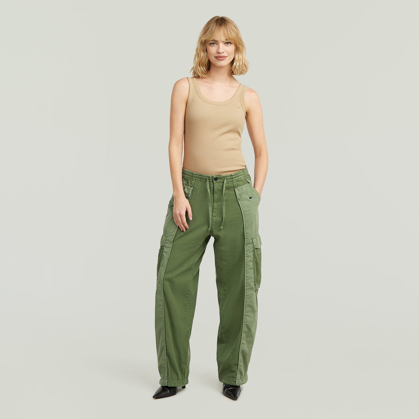Woman wearing fabric mix cargo pants in green, paired with a beige tank top, showcasing a stylish and functional design.
