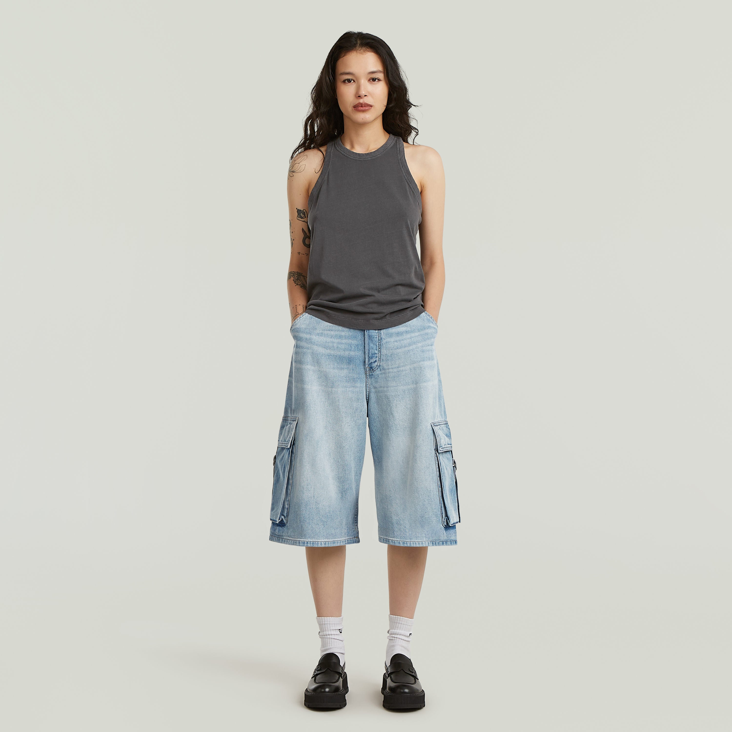 Mujer usando jorts cargo pockets de diseño ancho y talla media, con bolsillos cargo y color azul intermedio.