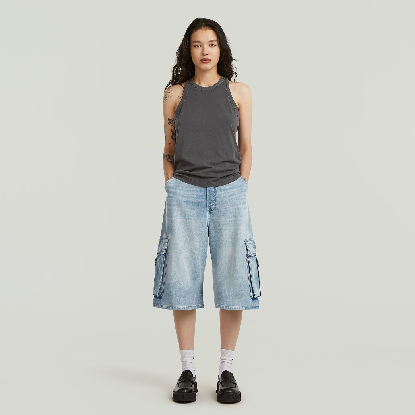 Mujer usando jorts cargo pockets de diseño ancho y talla media, con bolsillos cargo y color azul intermedio.