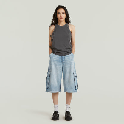 Mujer usando jorts cargo pockets de diseño ancho y talla media, con bolsillos cargo y color azul intermedio.