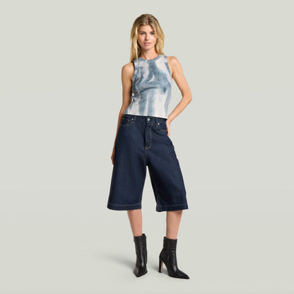 Jorts Patti borde limpio en azul oscuro, modelo con camiseta sin mangas, usando jorts de algodón reciclado con borde limpio.